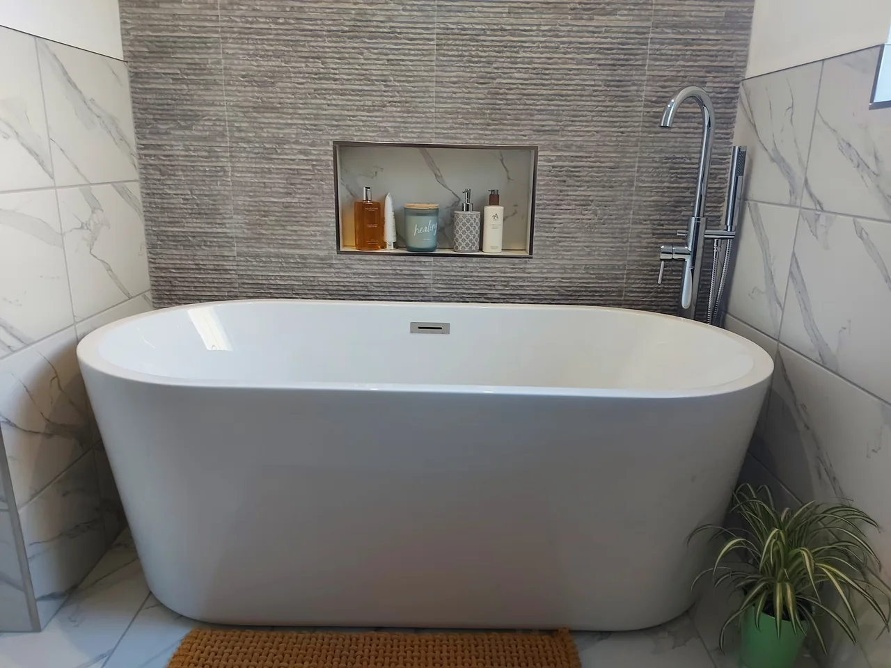 A finished bathroom with a freestanding white bath and neatly fitted tap