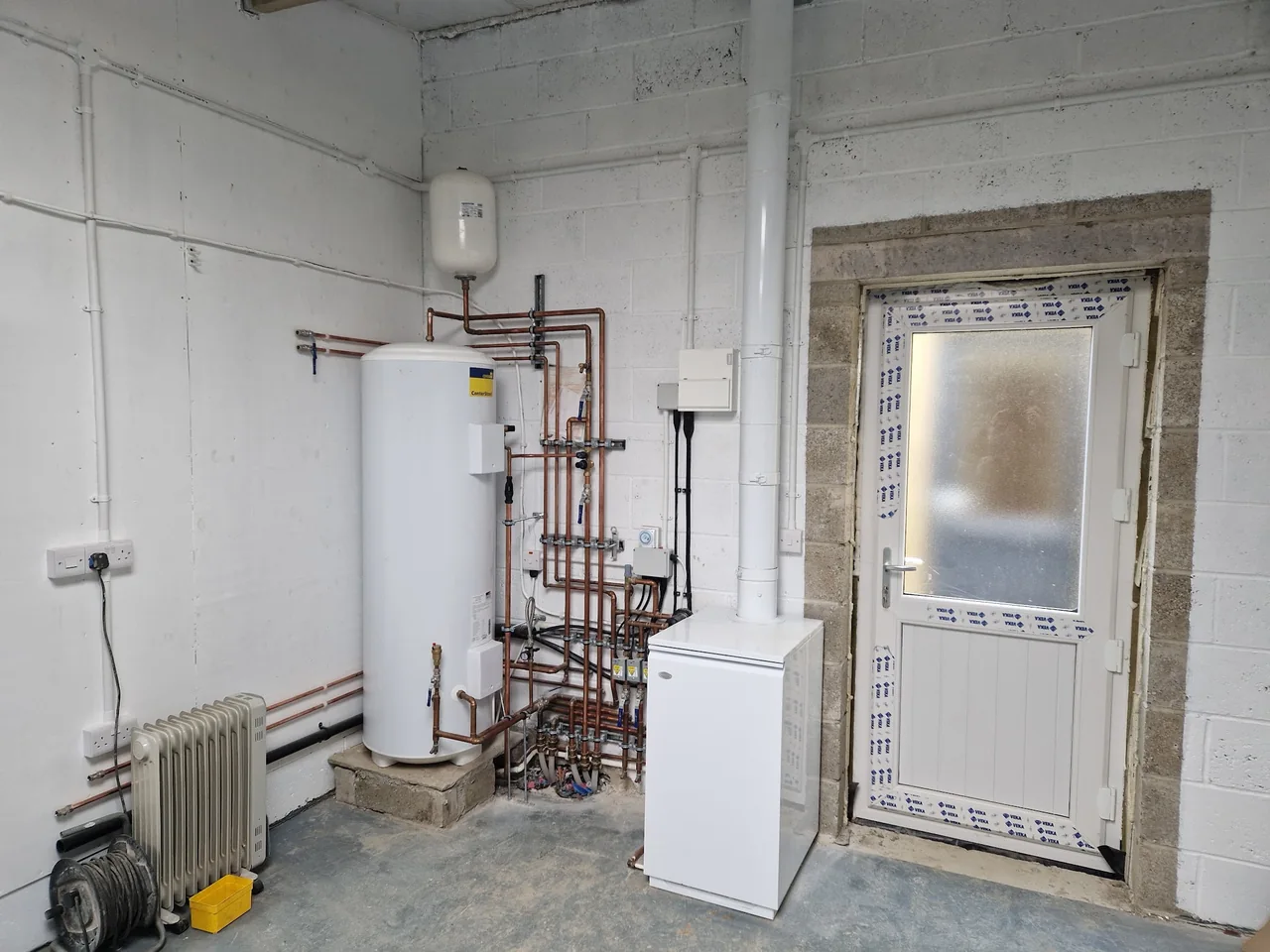 Heating plant room with a hot water cylinder and carefully arranged copper pipework