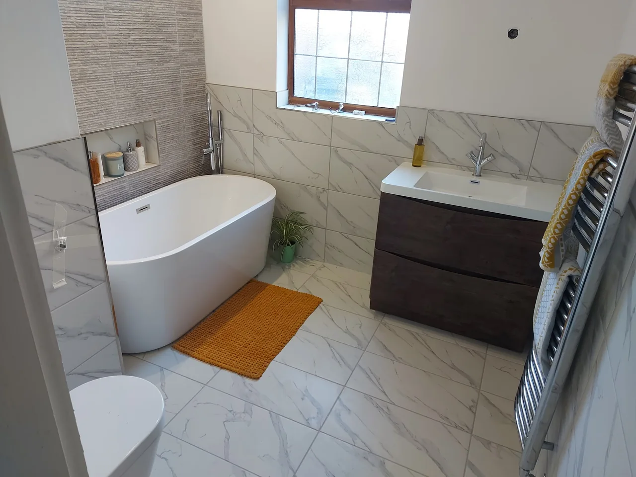 Completed bathroom with freestanding bath, basin and heated towel rail